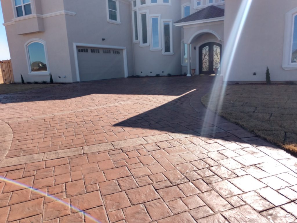 What else makes the entry into your home look better than a custom driveway? We love this stamped and stained concrete driveway! It adds a perfect accent to the gorgeous Spanish-style design on the exterior of this custom built home.